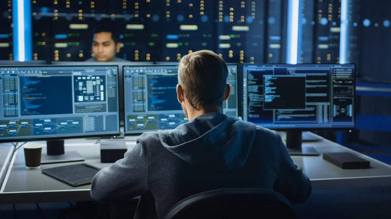 A person working at a desk with several monitors